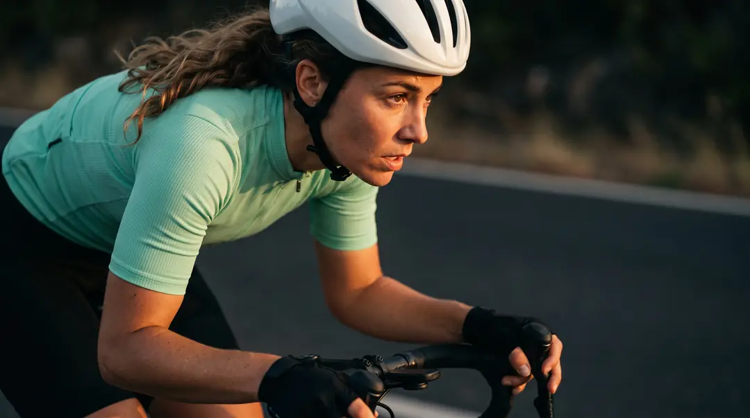 Yarış temposunda pedal çeviren bisikletçi ve yeşil forma